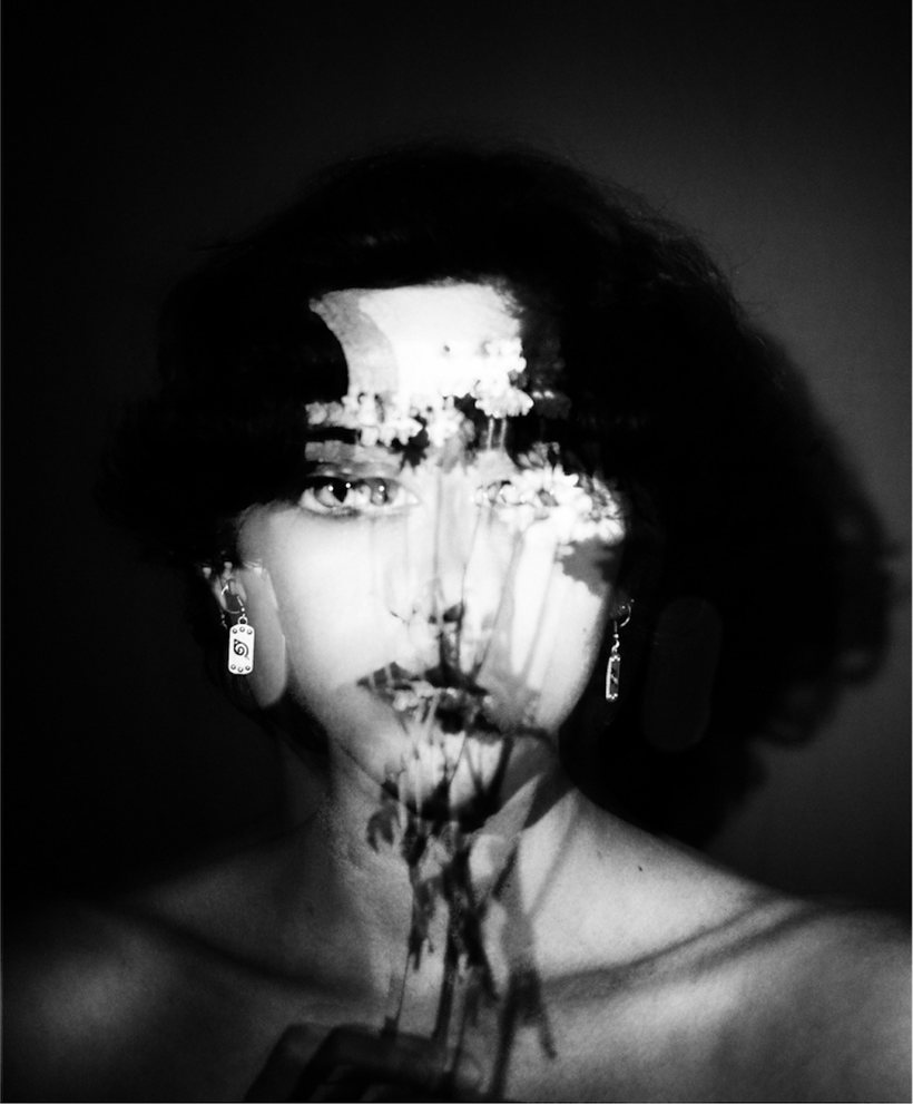 Portrait by Lilit L Hovhanni: a face in the dark, a projection of flowers falling across the forehead, eyes and mouth.